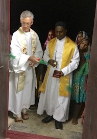 Fr. Tom cuts the ribbon while Fr. Thomas looks on. 